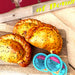 Three butter chicken curry pasties on a wood cutting board with three packs of geetas mango chutney.