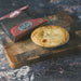 A baked veggie pie sits on a wooden cutting board next to its red and black Chucky branded packaging box, set against a dark rustic background.