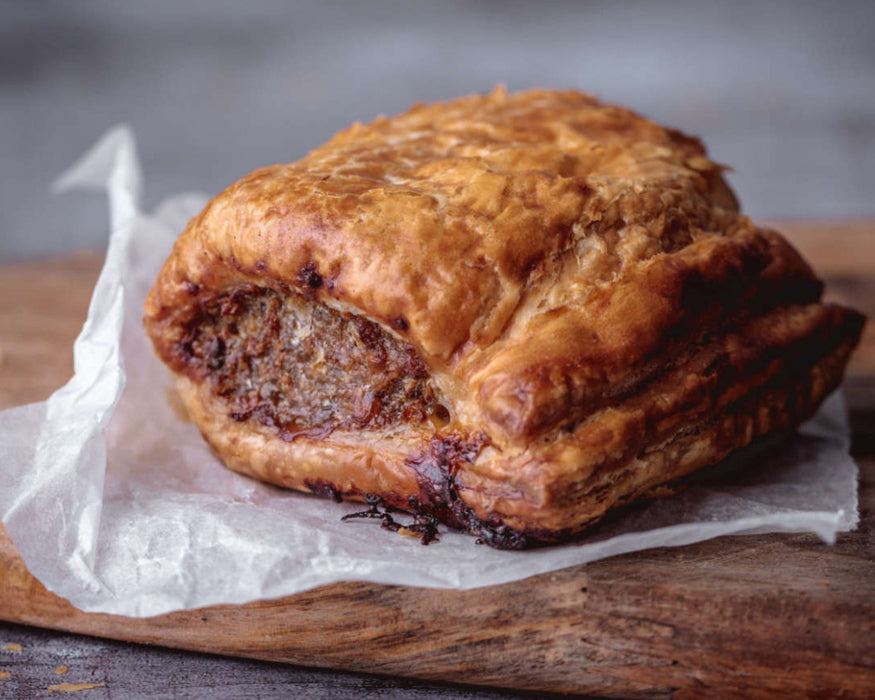 Puff pastry chunky sausage roll on a wooden board