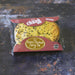 A wrapped pie made by 'Chunk' - Original Kickin' Chicken Curry Pie' in clear plastic wrapping with a red cardboard header, placed on a dark rustic surface.