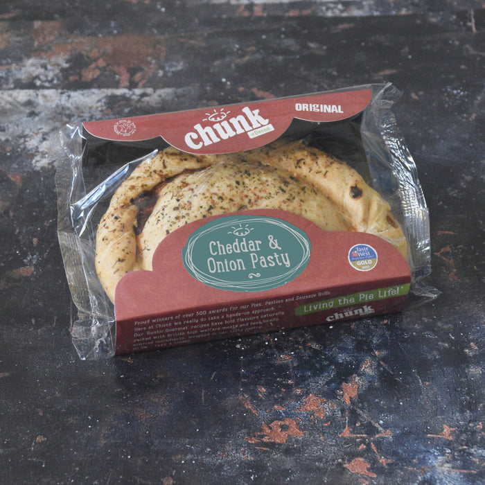 A packaged food product labeled 'chunk Original Cheddar & Onion Pasty' in clear plastic wrapping with a brown paper tray and label, placed on a dark textured surface.