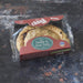 A packaged food product labeled 'chunk Original Cheddar & Onion Pasty' in clear plastic wrapping with a brown paper tray and label, placed on a dark textured surface.