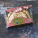 A Chunk original Veggie & Vegan pasty. The pasty is visible through the packaging, photographed on a dark textured surface.