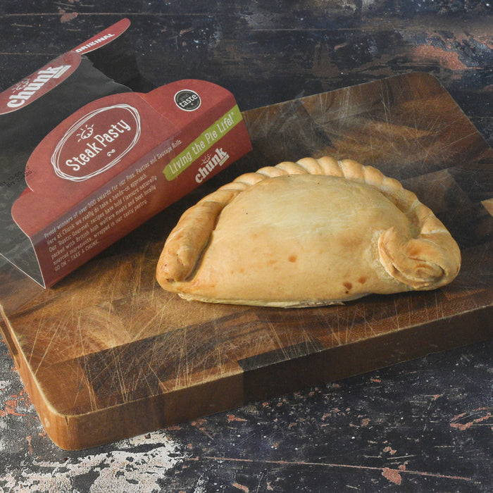 A baked Chunk Original Steak pasty, hand crimped edges on a wooden cutting board. Great Taste multi award winner