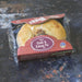 Chunk Original Steak & Kidney Pie in a clear plastic clamshell package with a red cardboard header, placed on a dark rustic surface.