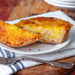 Chunk Original Homity Pie cut open served on a white plate with a fork and napkin on a wooden surface.