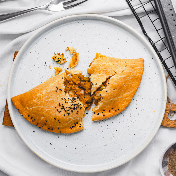Handmade gluten-free veggie and vegan pasty baked in Devon, served on a white plate.