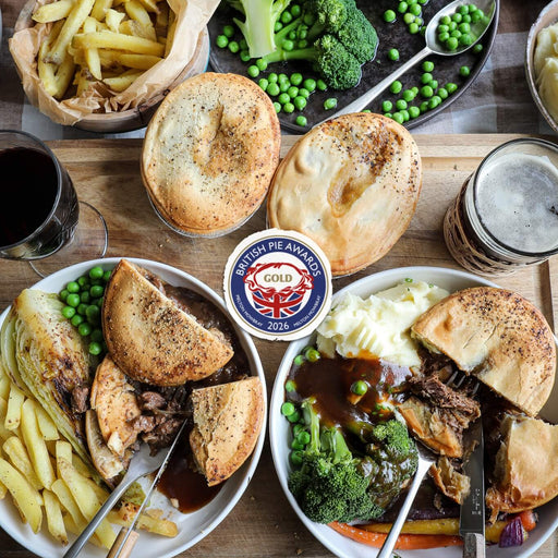 Plated Chunk pies with bread, vegetables, and gravy on a wooden board. New recipes Winners of Gold British Pie Awards 2026