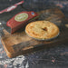 Chunk Original Lamb Pie on a wooden cutting board next to its packaging.