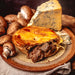 Chunk original Steak, Stilton & Mushroom Pie with mushrooms and blue cheese on a brown plate
