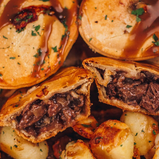 Close image of a Chunk Venison & Port Pie served with roast potatoes and gravy.